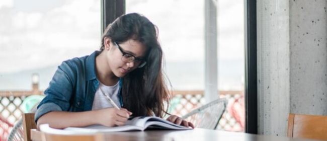 Girl studying at kitchen table.