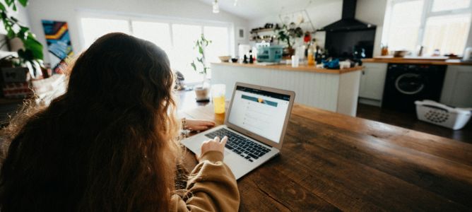 Girl working on a laptop at the kitchen table.