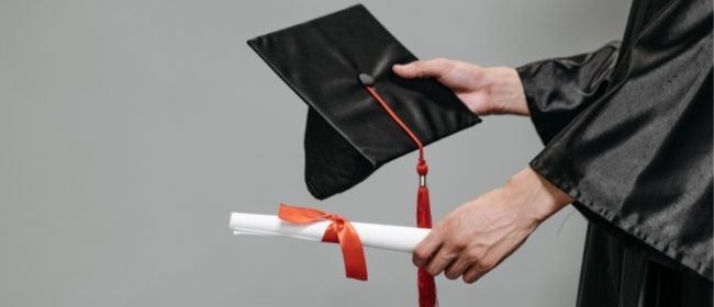 Hands extending out a diploma and graduation cap.