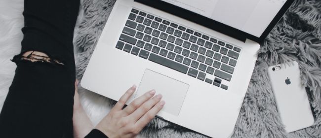 Person with ripped jeans using laptop.