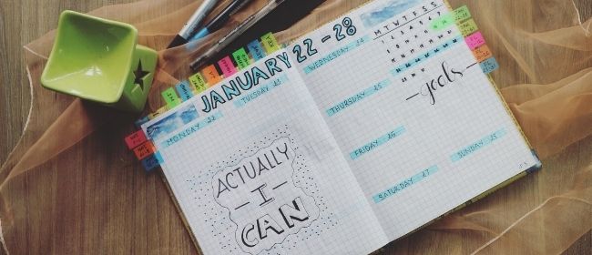 Daily planner with motivational message surrounded by markers and pens.