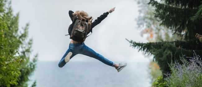 A girl jumping in the air while hiking.