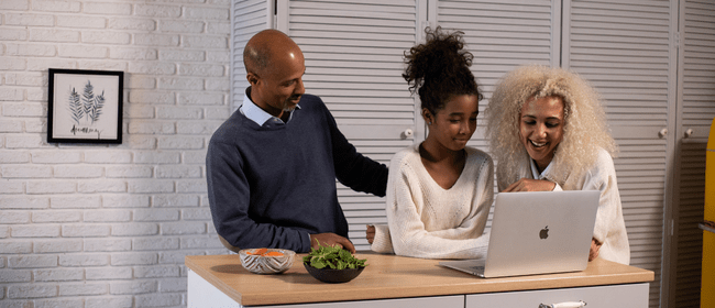 Father and mother looking at a laptop with their daughter