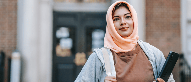 fident young woman carrying laptop.