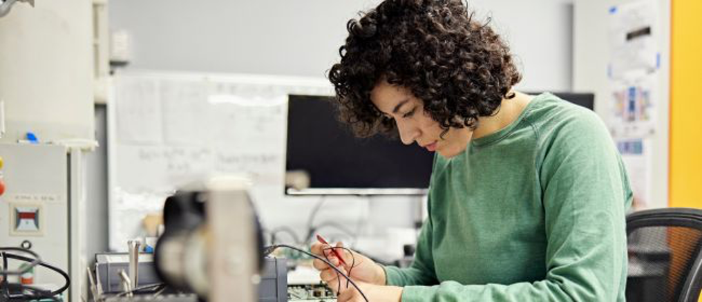 Young woman working on electrical components after earning an online technical diploma at JMHS.