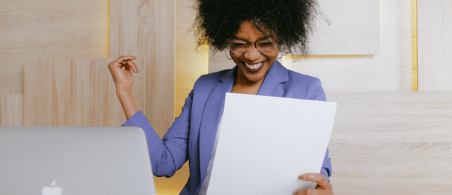 Women in suit looking accomplished as she is holding a document in hand.