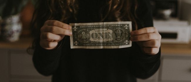 Girl holding dollar bill.