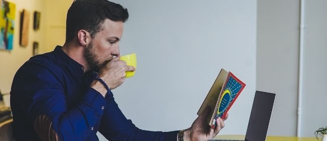 Man drinking and reading a book