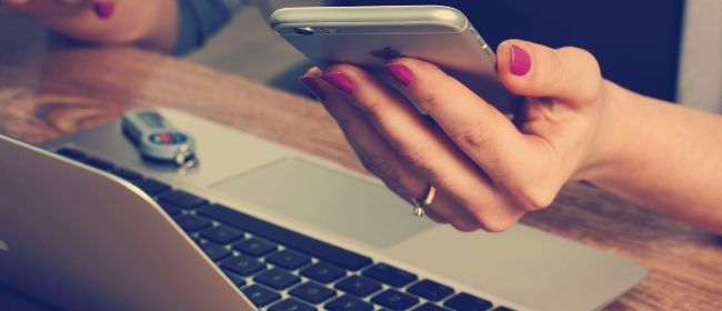 Woman using iphone and laptop.