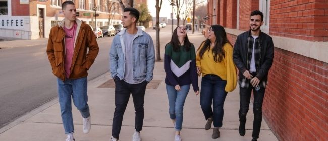 Five people walking down sidewalk