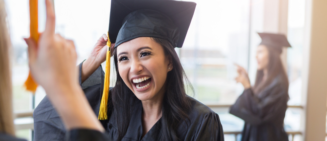 Young woman smiling in a graduation cap and gown.