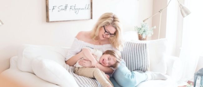 Woman playing with child on couch.