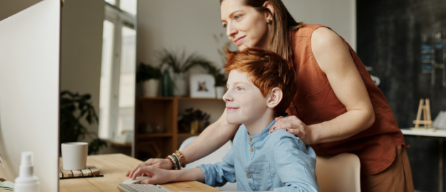 A woman and her son looking at a computer.