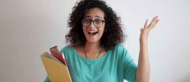 A female student holding books in her right hand while making a surprised expression.