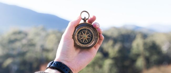 Person holding compass outdoors.