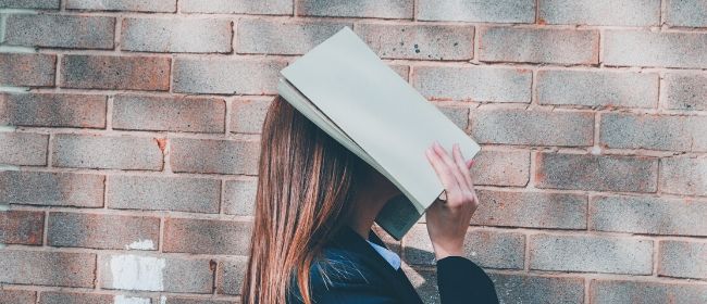 Girl holding book over face.