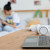 Teen playing on ukelele in background with laptop and desk in the foreground.