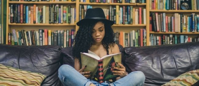 Girl sitting on couch reading a book