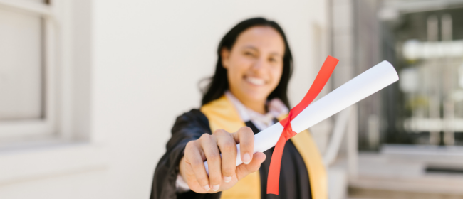 An out of focus woman holding out a high school diploma.