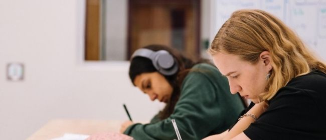 Girls at table writing.